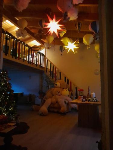 un grand ours en peluche assis dans une pièce avec un arbre de Noël dans l'établissement Ferienanlage Markus Nitsch, à Bärenstein