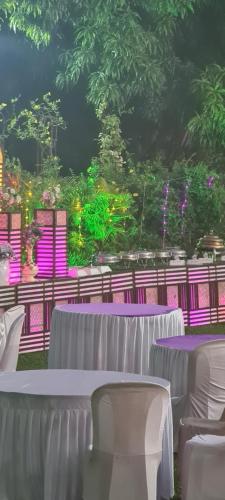 een set tafels met witte stoelen en paarse lampen bij Ashoka Lawns and Resort in Alibaug