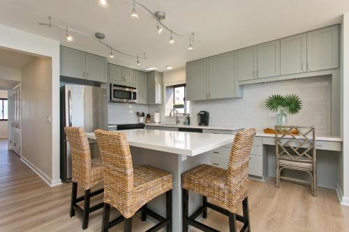 a kitchen with white cabinets and a kitchen island with chairs at High Floor Luxury Oceanfront at Waikiki Beach Tower in Honolulu