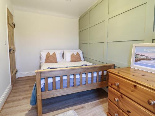 a small bedroom with a bed and a wooden dresser at Gwel Y Môr in Beaumaris