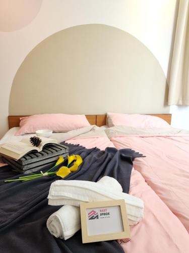 a bed with a pile of towels and a book at Ixora Coliving Lifestyle Homestay in Ayer Keroh