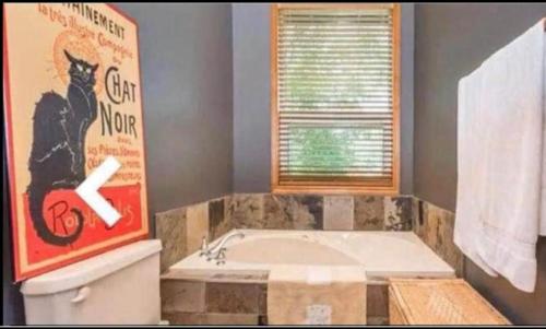 a bathroom with a tub and a picture of a cat on the wall at WATERFRONT LUXURY HOUSE/CHALET in Ragged Rapids