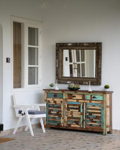 a mirror on top of a wooden dresser with a white bench at Ekaa House in Manāli