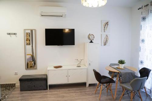 a living room with a table and a tv on the wall at Apartamentos Suites Cariátide in Plasencia
