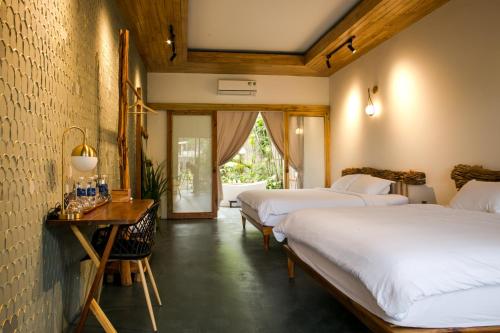 a hotel room with two beds and a desk and a window at Tổ Boutique Garden in La Gi