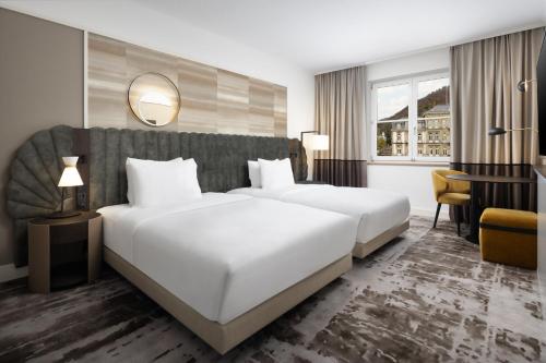 a hotel room with two beds and a desk at Hilton Heidelberg in Heidelberg