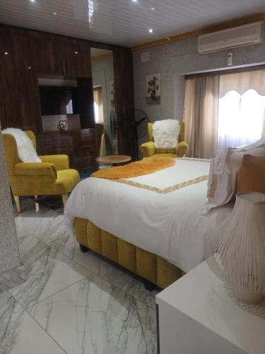 a bedroom with a large bed and two yellow chairs at Danko baba guest house & etc. in Welkom
