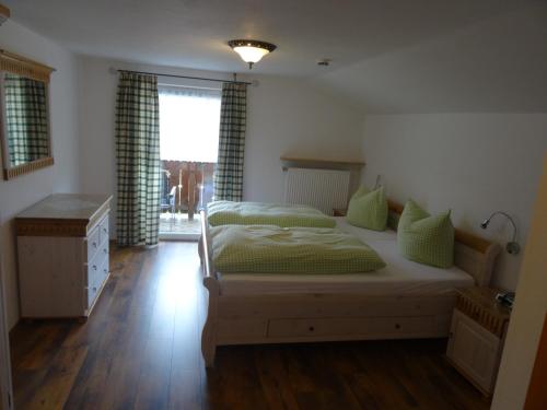 um quarto com uma cama com lençóis verdes e uma janela em Gästehaus Erika - Chiemgau Karte em Inzell