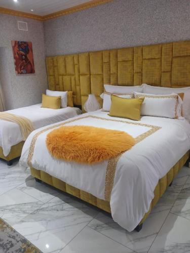 two beds in a hotel room with a large orange blanket at Danko baba guest house & etc. in Welkom