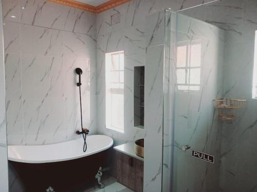 La salle de bains est pourvue d'une baignoire et d'une douche en verre. dans l'établissement Danko baba guest house & etc., à Welkom