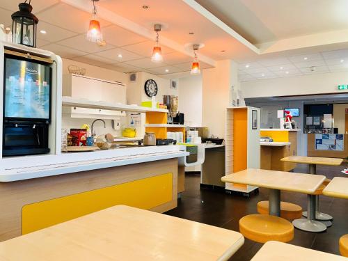 un restaurante con mesas y mostradores amarillos y blancos en ibis budget Roye, en Roye