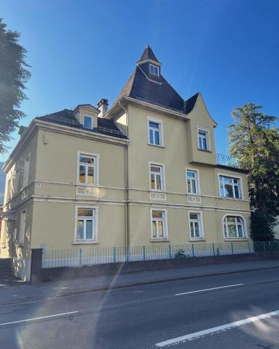 a yellow house with a black roof on a street at Villa Seeblick 1908 in Bregenz