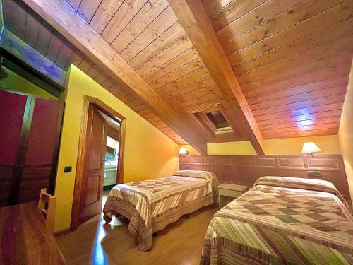 a room with two beds and a wooden ceiling at Hotel Solana in Benasque