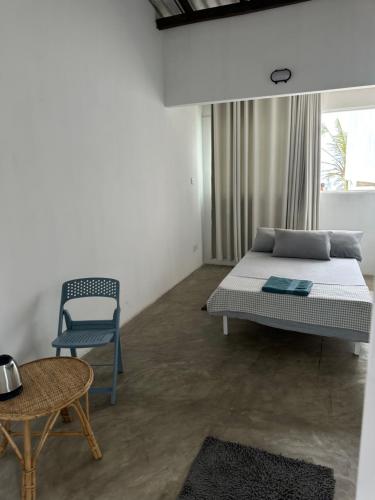 a bedroom with a bed and a chair and a table at Dip N Doze in Ahangama