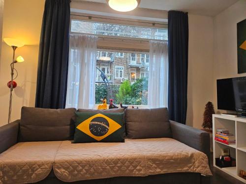 a couch in a living room with a window at Bos en Lommer Hotel - Erasmus Park area in Amsterdam