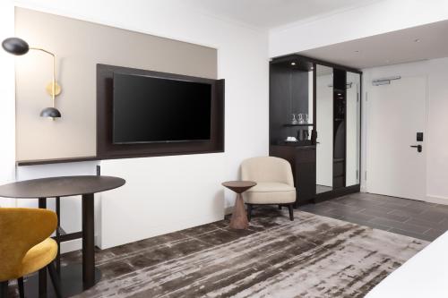 a living room with a tv and a table and chairs at Hilton Heidelberg in Heidelberg