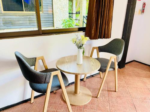a table with two chairs and a vase with flowers at Boomerang Village Resort Kata in Kata Beach