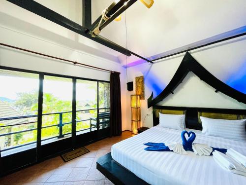 a bedroom with a large bed with two blue shoes at Boomerang Village Resort Kata in Kata Beach