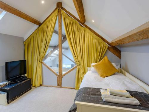 um quarto com cortinas amarelas, uma cama e uma televisão em 5 Bed in Abersoch 55385 em Bottwnog