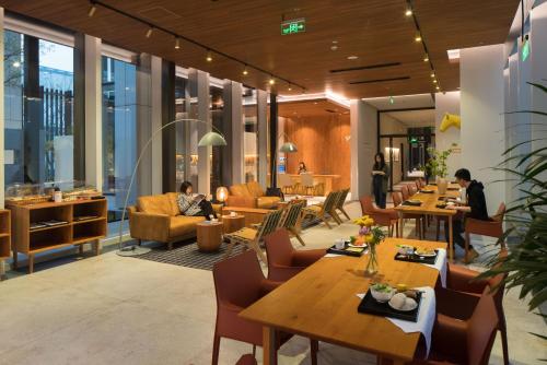 a lobby of a building with tables and chairs at Wuyu Hotel Chongqing Yangjiaping The Mixc in Chongqing