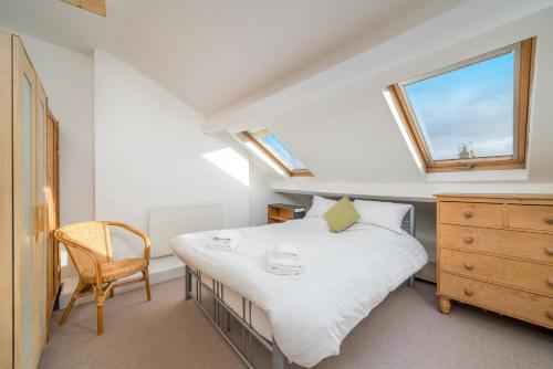 um quarto com uma cama, uma cadeira e uma janela em ALTIDO Cosy maisonette near Abbey Road em Londres
