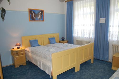 a bedroom with a yellow bed with blue walls and windows at Guest house Hošek in Senorady