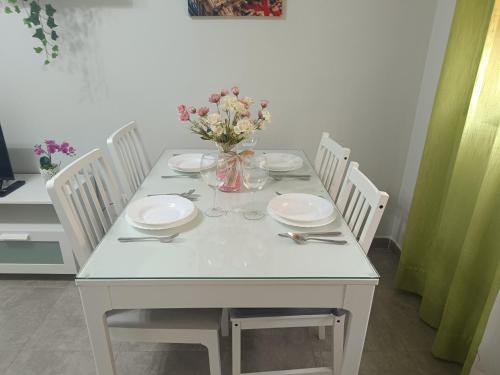 un tavolo bianco con piatti e un vaso di fiori di EL BOSQUE 1 - Parking gratis a Toledo
