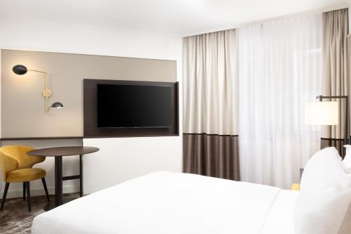 a hotel room with a bed and a tv and a table at Hilton Heidelberg in Heidelberg