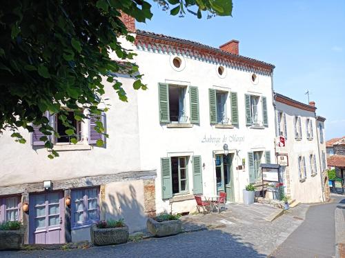 un bâtiment blanc avec volets verts dans une rue dans l'établissement Auberge De Margot, à Usson