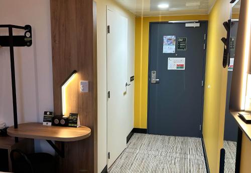a hallway with a blue door and a wooden table at B&B HOTEL Cergy Saint-Christophe Gare in Cergy