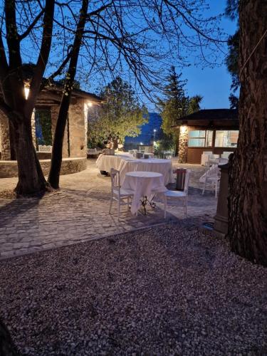 a table with white tables and chairs under a tree at Tenuta Oliva in Fisciano