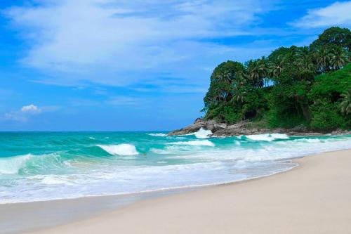 a beach with a group of trees and the ocean at Holiday Inn Resort Phuket Surin Beach, an IHG Hotel in Surin Beach