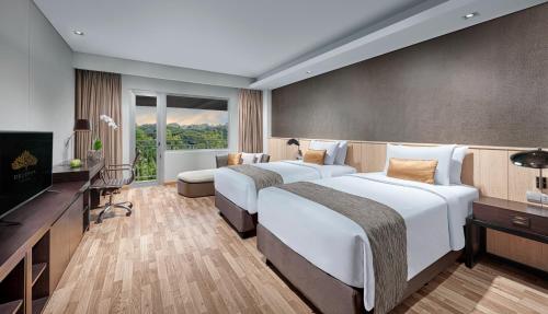 a hotel room with two beds and a television at Delonix Hotel Karawang in Karawang