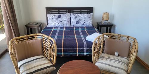 - une chambre avec deux chaises en osier et un lit dans l'établissement Beachfront Bed & Breakfast, à San Jose