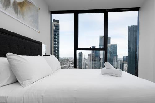 a bedroom with a white bed with a large window at City Lookout with Amenities in Melbourne