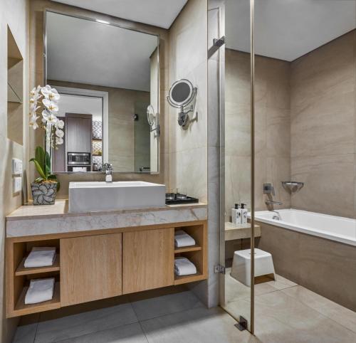 a bathroom with a tub and a sink and a bath tub at Delonix Hotel Karawang in Karawang