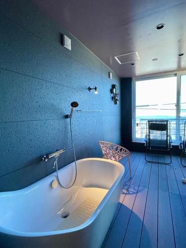 a bath tub in a bathroom with a large window at Hakodate As time flies -Sauna&Villa- 函館 時のたつままに in Hakodate