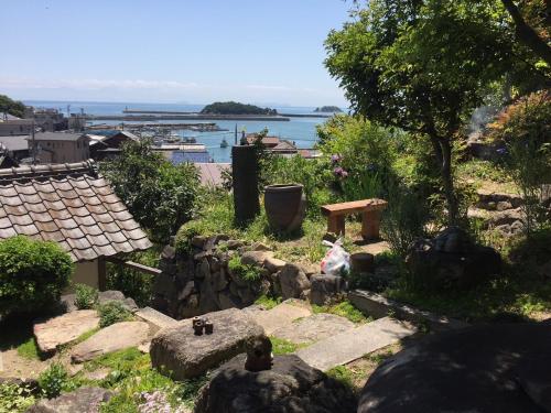 a garden with a bench and a table and water at 城跡石垣上の絶景古民家宿 鞆城茶屋庵 in Tomo