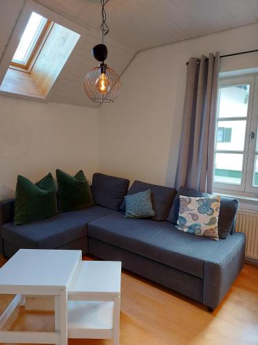 a living room with a blue couch and two windows at Ferienwohnungen Schneiderhäusl inkl. Chiemgaukarte in Ruhpolding