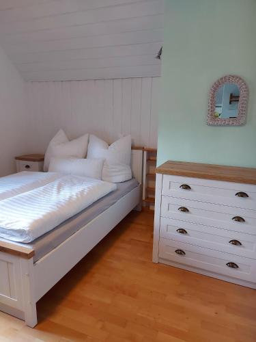 a bedroom with a white bed and a dresser at Ferienwohnungen Schneiderhäusl inkl. Chiemgaukarte in Ruhpolding
