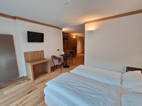 Dormitorio con cama, escritorio y TV en Hotel Ideal, en Madonna di Campiglio