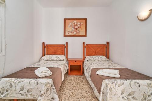Habitación con 2 camas y toallas. en Capistrano1, en Nerja