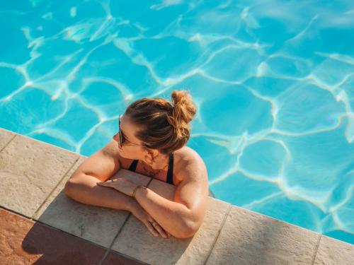 a woman sitting on the edge of a swimming pool at Grand Mercure Ise-shima Resort & Spa in Shima