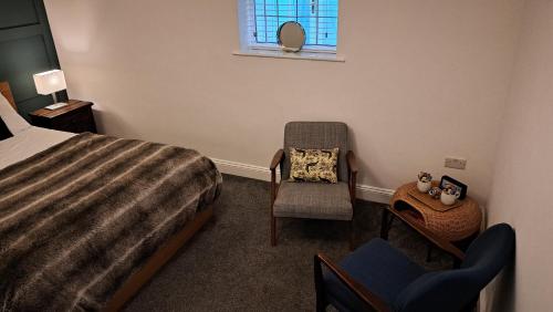 a bedroom with a bed and a chair and a window at The Old Vicarage in Flore