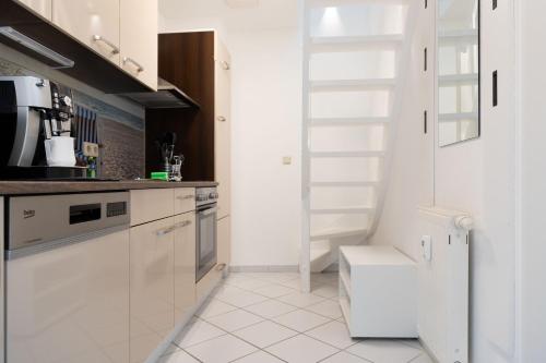 a kitchen with white cabinets and a white floor at Wellness-Ferienwohnung Strandurlaub Baabe in Baabe