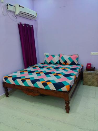 a bed with a colorful comforter in a room at VJ VILLA HOME STAY PURPLE ROOM in Puducherry