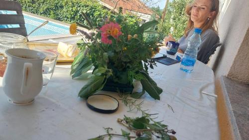 uma mulher sentada à mesa com um vaso de flores em Cvrkut Ptica 1 em Mladenovac