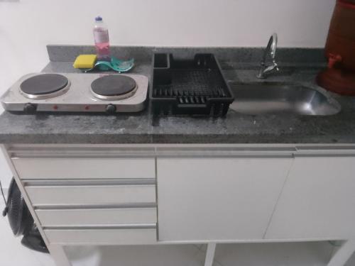 a kitchen counter with a stove and a sink at Studio Gru in Guarulhos