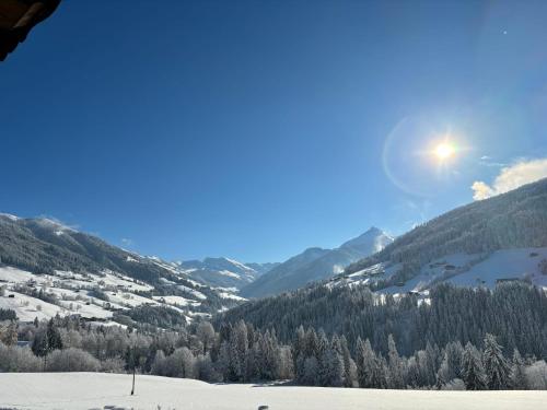 a view of a snow covered mountain with the sun in the sky at Haus Schmetterling in Alpbach