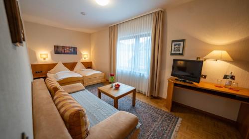 a living room with a couch and a television at Hotel Restaurant St. Germanshof in Bobenthal